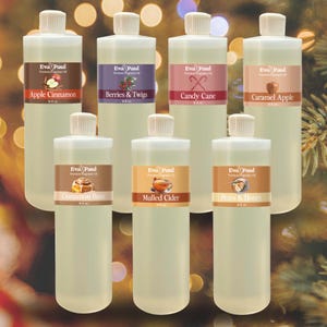May include: A collection of clear plastic bottles with white caps, each labeled with a different fragrance name. Scents include Apple Cinnamon, Berries & Twigs, Candy Cane, Caramel Apple, Cinnamon Buns, Mulled Cider, and Pears & Honey.