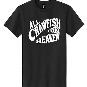 May include: Black t-shirt with the white text "ALL CRAWFISH GO TO HEAVEN" in a stylized font. The shirt is a crew neck and has short sleeves. The text is arranged in a curved design, with the word "CRAWFISH" forming a central element.