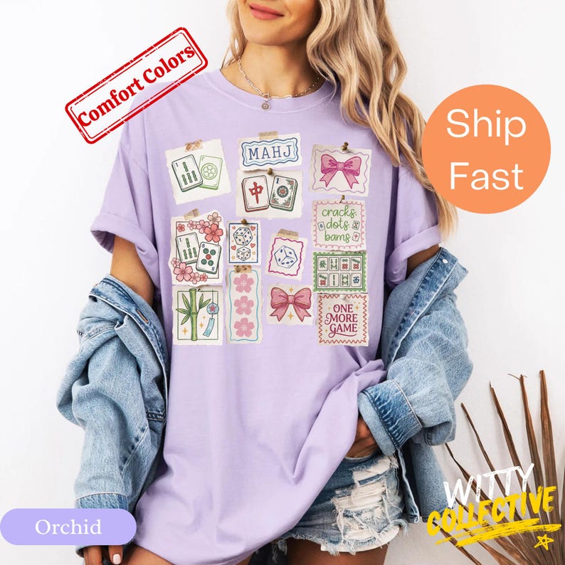 May include: Orchid-colored t-shirt featuring a collage of Mahjong-themed illustrations. The design includes tiles, dice, and decorative elements with the text "MAHJ" and "ONE MORE GAME". The shirt has short sleeves and a relaxed fit.