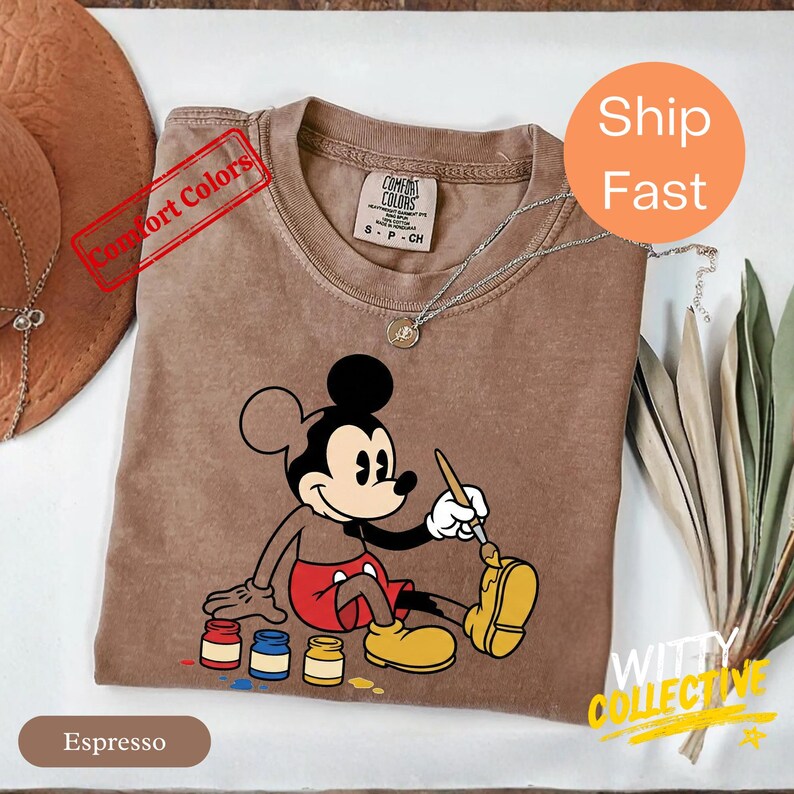 May include: A white ceramic mug with a black handle and the text "But First, Coffee" in a bold, black font. The mug is set against a blurred background, suggesting a cozy setting. The mug appears to be approximately 4 inches tall.