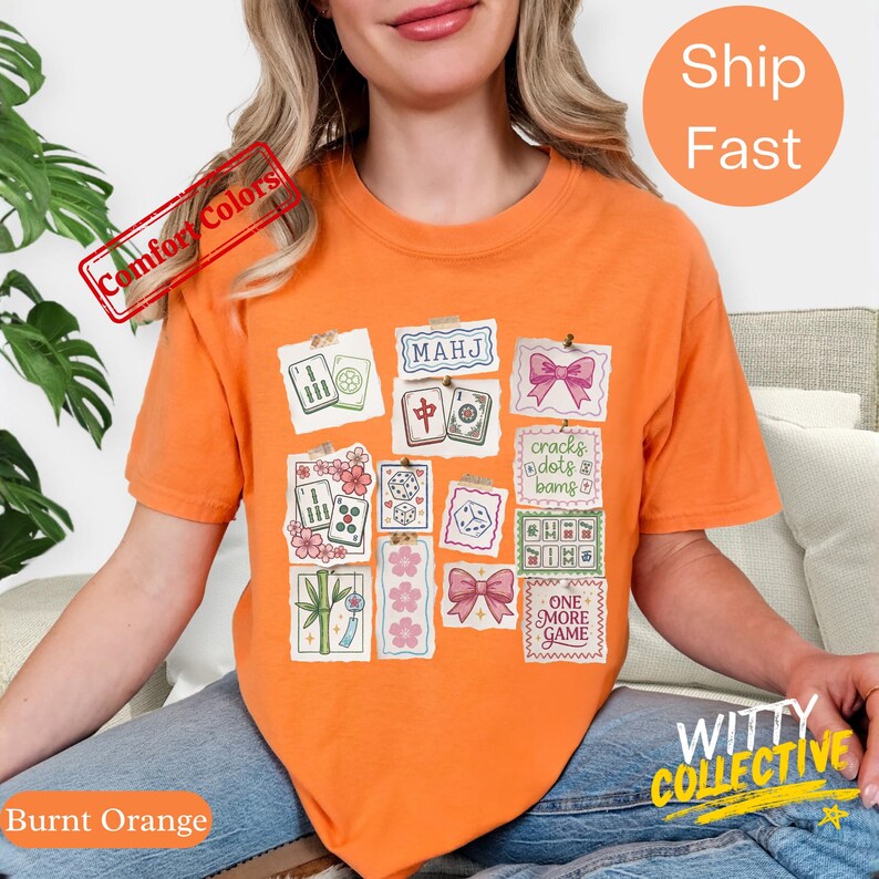 May include: Burnt orange t-shirt with a collage of Mahjong tile illustrations and text. The shirt features the words "MAHJ", "cracks dots & bams", and "ONE MORE GAME". The shirt is from the "Comfort Colors" collection.