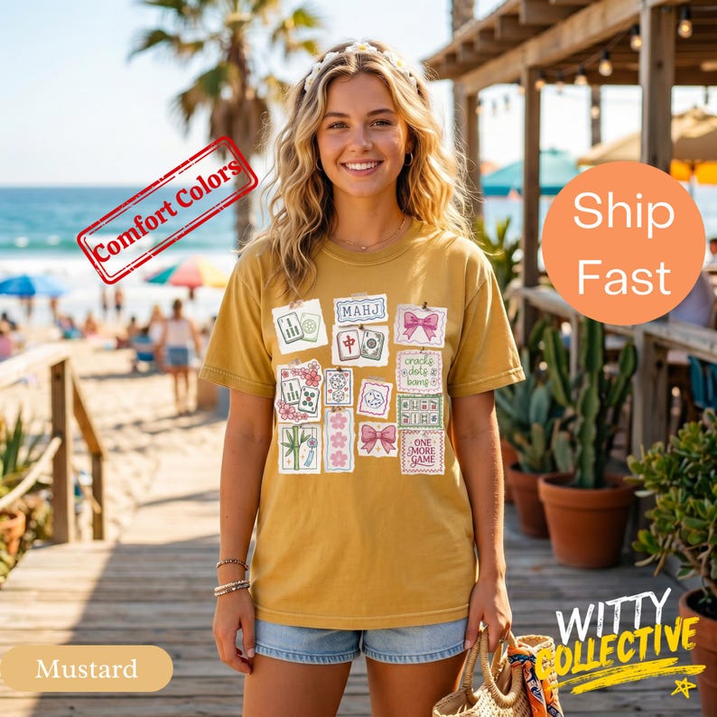 May include: Mustard-colored t-shirt with various graphic patches, including text and illustrations. The shirt features the text "MAHJ" and "ONE MORE GAME". The words "Comfort Colors" and "Ship Fast" are also visible.