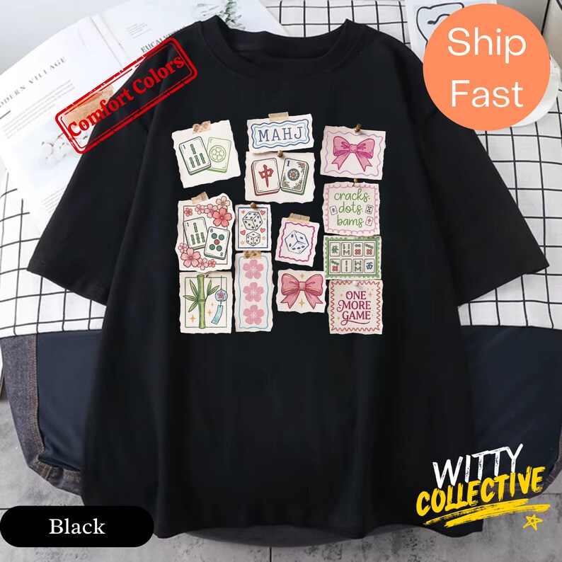 May include: Black t-shirt featuring a collage of colorful Mahjong-themed graphics, including tiles, flowers, and bows. The shirt has the text "MAHJ" and "ONE MORE GAME". The shirt is from the "WITTY COLLECTIVE" and has "Comfort Colors" printed on it.