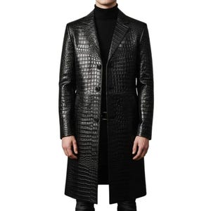 May include: A black long coat featuring a textured crocodile skin pattern throughout the exterior. The coat has a notched lapel collar, long sleeves, and a front button closure. It is worn over a black turtleneck sweater, creating a monochromatic look.