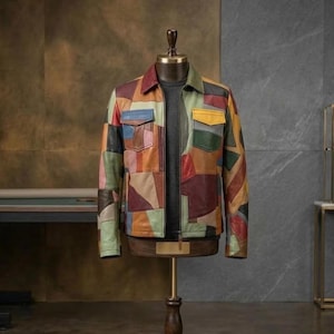 Puede incluir: Una chaqueta de cuero multicolor con un diseño de patchwork de varias formas geométricas en tonos rojo, amarillo, azul, verde y marrón. La chaqueta incluye una cremallera frontal completa, un cuello en punta y dos bolsillos en el pecho con solapas.