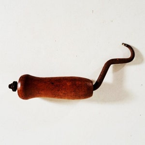 May include: A wooden handled hook with a rusty metal hook. The hook is bent at a 90-degree angle.