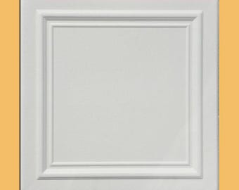 May include: A white, square cabinet door with a recessed panel and decorative moulding. The door is set against a light orange background. The design features a raised, rectangular inner panel.