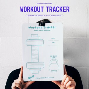 Könnte beinhalten: Ein weißes, druckbares Trainingsprotokoll mit blauen Strichzeichnungen einer Hantel und einer Kettlebell. Der Text lautet Workout Tracker, train. focus. achieve., My Daily Goal und Every repetition counts. Enthält Felder für Monat und Jahr.