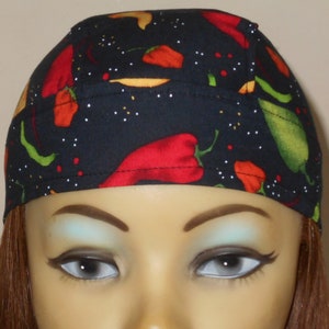 May include: A black skull cap with a red and green chili pepper pattern. The cap is worn on a mannequin head with brown hair.