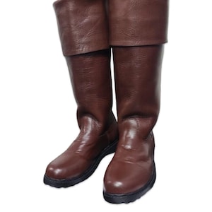 May include: A pair of brown leather knee-high boots with folded-over tops. The boots have a smooth, glossy finish and black soles. These boots are suitable for costume or everyday wear.