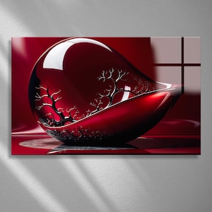 Può includere: Una ciotola decorativa in vetro rosso lucido a forma di goccia. L'interno presenta un design ad albero stilizzato in argento. La ciotola poggia su una superficie riflettente, con uno sfondo rosso.