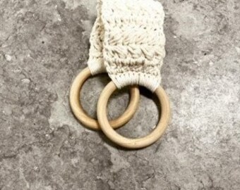 Puede incluir: Toallero de ganchillo color crema con dos anillos de madera natural. El soporte presenta un diseño texturizado y tejido. Los anillos son redondos y lisos, proporcionando un diseño simple y funcional para el baño o la cocina.
