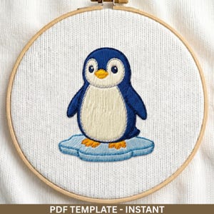 May include: Embroidered penguin design in a wooden embroidery hoop. The penguin is blue and white, standing on a blue ice floe. The text "PDF TEMPLATE - INSTANT" is at the bottom of the image. The background is white.