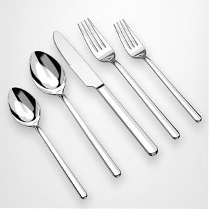 Può includere: Un set di posate in acciaio inossidabile lucido, composto da due cucchiai, un coltello e due forchette. Gli utensili sono disposti diagonalmente su uno sfondo bianco, riflettendo la luce. Le posate hanno un design semplice e moderno.