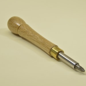 May include: A wooden screwdriver with a light brown handle and a silver metal tip. The handle has a rounded end and a brass-coloured metal ring near the tip. The screwdriver is designed for use with Phillips head screws.