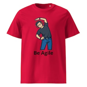May include: A red t-shirt with a cartoon illustration of a person wearing glasses and headphones, stretching. The text "Be Agile" is printed in black below the illustration. The shirt is made of a soft material.
