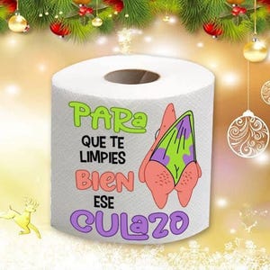 Puede incluir: Un rollo de papel higiénico blanco con un dibujo de un personaje de dibujos animados con un bañador morado y verde. El texto en el rollo dice "PARA QUE TE LIMPIES BIEN ESE CULAZO."