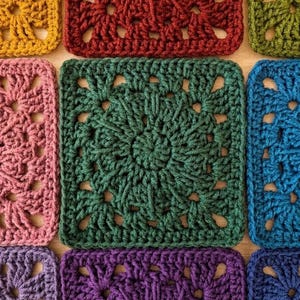 Peut inclure: Une collection de motifs carrés au crochet disposés en grille. Chaque carré présente un motif circulaire central rayonnant vers une bordure carrée. Les couleurs incluent le jaune moutarde, le rouge foncé, le vert olive, le rose, le vert sapin, le bleu, le violet et le bleu marine.