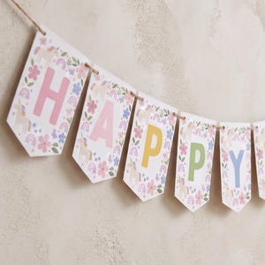 May include: A decorative banner featuring white pennants strung on twine. Each pennant displays a letter spelling HAPPY in pastel pink, yellow, green, and blue. The design includes illustrations of unicorns, rainbows, and small floral motifs.