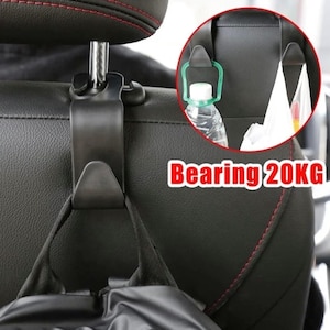 May include: Black car seat headrest hook with a silver metal post. The hook is holding a black bag. A close-up shows a green plastic hook holding a water bottle. The text "Bearing 20KG" is visible.