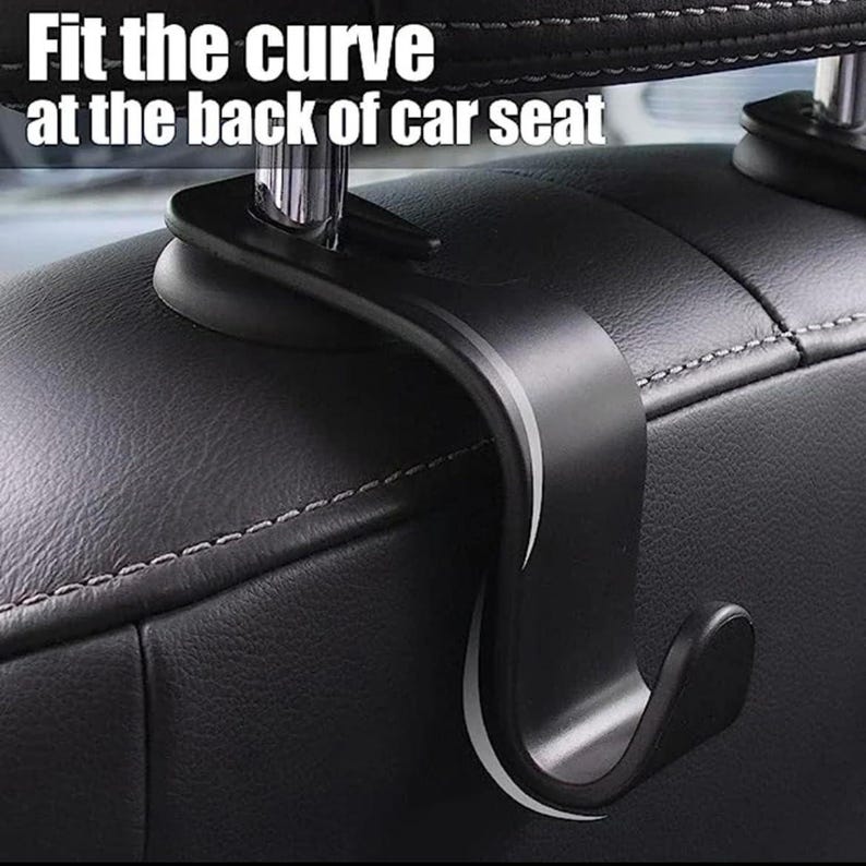 May include: A black car seat hook with the text "Fit the curve at the back of car seat". The hook is designed to attach to the headrest and hang items. The hook is made of a durable material and has a curved design.