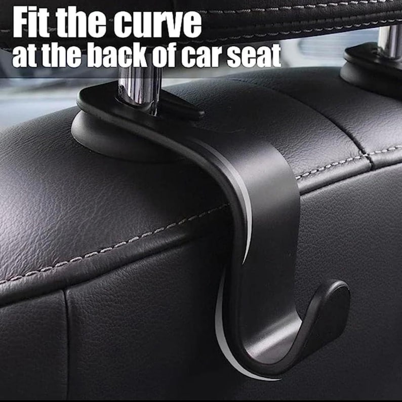 May include: A black car seat hook with the text "Fit the curve at the back of car seat" in white. The hook is designed to attach to the headrest and hang items. The hook is made of a durable material and has a curved design.