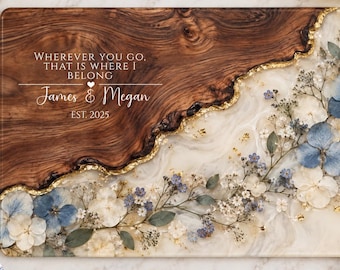 Peut inclure: Une planche de service rectangulaire en bois avec une section en bois foncé et une section en résine blanche incrustée de fleurs séchées bleues et blanches. Un bord doré sépare les deux matériaux. Le texte indique : WHEREVER YOU GO, THAT IS WHERE I BELONG, James & Megan, EST. 2025.