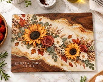 Peut inclure: Une planche de service rectangulaire en bois avec une incrustation centrale en résine ornée d'un arrangement floral de tournesols, de roses et de feuilles d'automne. Le texte "ROBERT & JESSICA EST. 2015" est gravé sur la partie en bois foncé.
