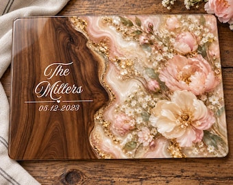Peut inclure: Une planche de service rectangulaire avec une section en bois foncé à gauche et une section en résine brillante à droite ornée de fleurs roses, de gypsophile blanc et de flocons dorés. Le texte indique The Millers et 05.12.2023.