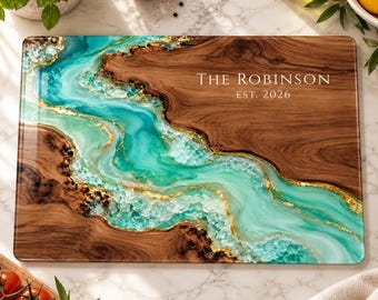 Peut inclure: Une planche à découper rectangulaire en bois avec une incrustation de résine turquoise et bleu sarcelle, agrémentée de feuilles d'or. Le texte THE ROBINSON EST. 2026 est gravé en blanc sur la surface en bois lisse.