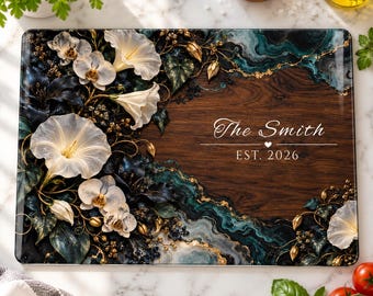 Peut inclure: Une planche à découper rectangulaire en verre avec un centre en grain de bois foncé, des fleurs blanches, des motifs de marbre bleu sarcelle et doré, et le texte The Smith EST. 2026 imprimé en blanc au centre.