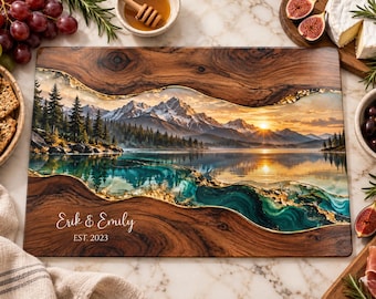 Peut inclure: Une planche de service rectangulaire en bois avec une incrustation centrale en résine représentant un paysage de lac de montagne au coucher du soleil. Le design inclut des accents de feuilles d'or et le texte "Erik & Emily" et "EST. 2023".