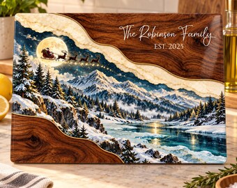 Peut inclure: Une planche à découper rectangulaire en verre illustrant un paysage de montagne hivernal avec une forêt enneigée, une rivière gelée et le Père Noël en traîneau devant la pleine lune. Le texte indique The Robinson Family EST. 2025.