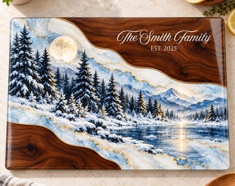 Peut inclure: Une planche à découper rectangulaire présentant un paysage hivernal avec des pins enneigés, une pleine lune et un lac gelé. Le motif inclut un grain de bois foncé et le texte The Smith Family EST. 2025 en écriture blanche.