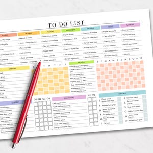 May include: A white To-Do List planner with a red pen. The planner is organized by day, week, month, and quarter, with sections for everyday, quarterly, semi-annual, and annual tasks. A smartphone and a small plant are in the background.