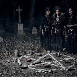 May include: Three people in black attire stand in a graveyard, gathered around a white pentagram drawn on the ground. The scene includes candles, small bowls, and other ritualistic items, creating a mysterious and occult atmosphere.