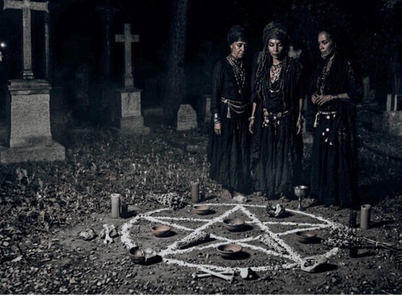 May include: Three people in black attire stand in a graveyard, gathered around a white pentagram drawn on the ground. The scene includes candles, small bowls, and other ritualistic items, creating a mysterious and occult atmosphere.