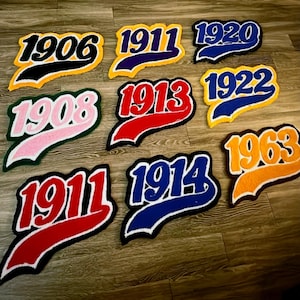 May include: Nine colorful, embroidered patches with various years, including 1906, 1911, 1920, 1908, 1913, 1922, 1911, 1914, and 1963. Each patch features a different color scheme, with the numbers in bold, outlined in white, and set against a contrasting background.