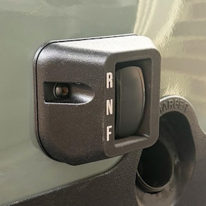 May include: Close-up of a black control panel with a rocker switch labeled "R", "N", and "F". The panel is mounted on a green surface. The word "CHARGER" is partially visible.