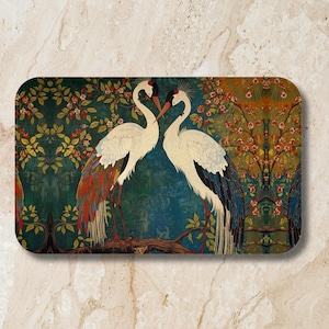 May include: Rectangular decorative mat featuring two white cranes with red and black accents, facing each other. The background is a teal and green floral design with a brown branch.