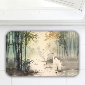 May include: Rectangular decorative mat featuring a serene watercolor scene. The artwork depicts white egrets in a bamboo forest with a soft, muted color palette of greens, yellows, and browns. The mat has rounded corners and is placed on a white tiled surface.