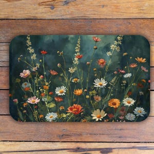 May include: Rectangular doormat featuring a watercolor painting of wildflowers in shades of white, orange, pink, and red against a dark green background. The floral design is detailed and artistic, creating a welcoming entrance.