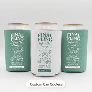 May include: Three custom can coolers with the text "FINAL FLING before the ring" in a script font. The coolers are teal and white, with wedding-themed graphics. The text "OLIVIA'S BACH MIAMI, FL 2026" is also printed on the coolers.