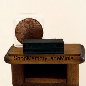 May include: A miniature black rectangular box with carved details sits on a small wooden table. A penny in a clear case is next to the box. The table has a shelf and rounded edges. The text "ShopMemoryLaneMinis" is on the table.