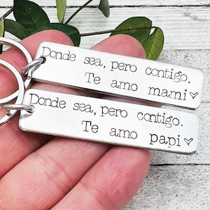 May include: Two silver keychains with the text "Donde sea, pero contigo. Te amo mami" and "Donde sea, pero contigo. Te amo papi" engraved on them.