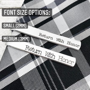 Puede incluir: Dos pasadores de corbata plateados con el texto "Return With Honor" grabado en ellos. Los pasadores de corbata se muestran sobre una tela de cuadros negros y blancos. El texto "SMALL (2MM)" y "MEDIUM (3MM)" se muestra sobre los pasadores de corbata.