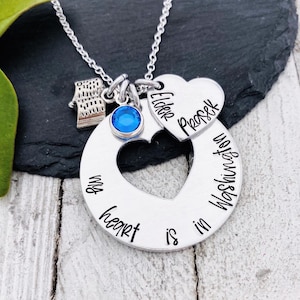 Puede incluir: Un collar de plata con un dije que dice "My heart is in Washington" y un dije de corazón más pequeño que dice "Elder Prescott". El collar también tiene un pequeño dije de cristal azul y un dije que parece un libro abierto.