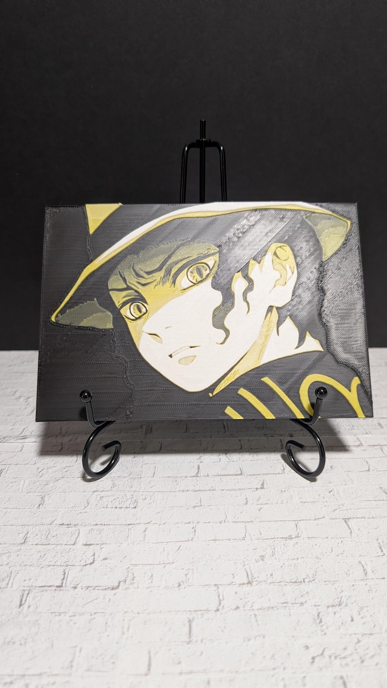 May include: A black and yellow illustration of a character with a hat, displayed on a black easel. The artwork features a detailed face with large eyes and a focused expression. The color palette is primarily black and yellow.