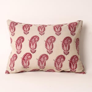 May include: Rectangular cushion featuring a cream-coloured background adorned with a repeating pattern of burgundy paisley motifs. A soft furnishing item for home decor.
