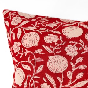May include: A square throw cushion cover featuring a vibrant red background with a repeating cream-coloured botanical print. The pattern displays stylised pomegranate fruits, delicate flowers, and leafy vines across the entire fabric surface.